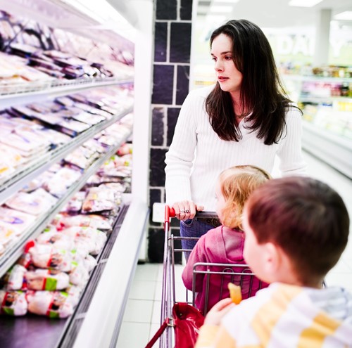 moeder met kinderen in winkelwagen kopen vlees in supermarkt-500x495